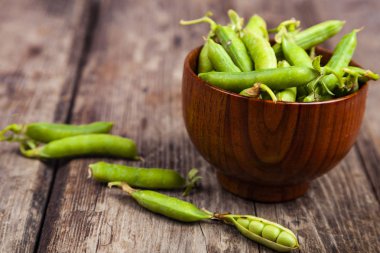 Tahta bir kasede yeşil bezelyeler. 