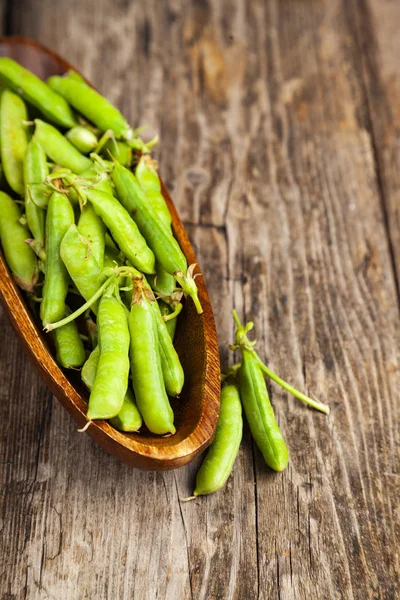 Groene erwten in een houten schaal. — Stockfoto