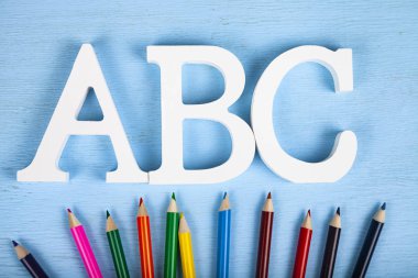  Mektuplar Abc ve mavi ahşap arka plan üzerinde renkli kalemler.