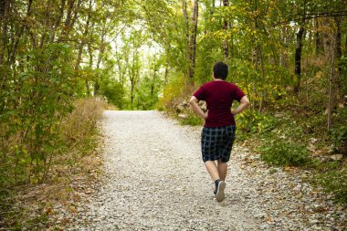Genç adam bir dağ ormanında bir yol boyunca yürüyor. 