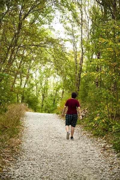 Jonge man loopt langs een pad in een berg woud. — Stockfoto