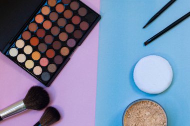 Pembe-mavi arka planda kozmetik ve fırçalar. Dekoratif kozmetik.
