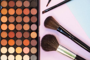 Pembe-mavi arka planda kozmetik ve fırçalar. Dekoratif kozmetik.