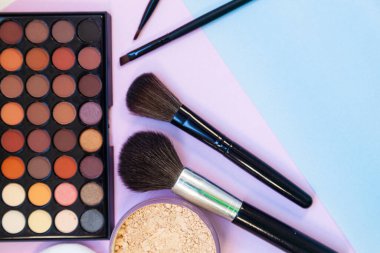 Pembe-mavi arka planda kozmetik ve fırçalar. Dekoratif kozmetik.