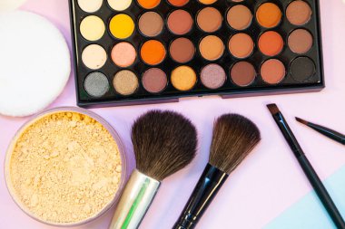 Pembe-mavi arka planda kozmetik ve fırçalar. Dekoratif kozmetik.