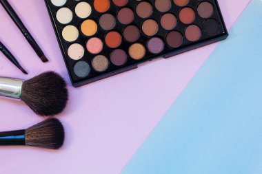 Pembe-mavi arka planda kozmetik ve fırçalar. Dekoratif kozmetik.
