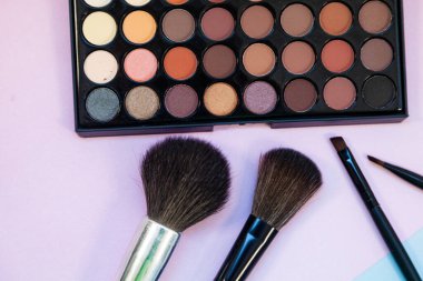 Pembe-mavi arka planda kozmetik ve fırçalar. Dekoratif kozmetik.