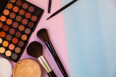 Pembe-mavi arka planda kozmetik ve fırçalar. Dekoratif kozmetik.