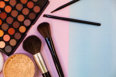Pembe-mavi arka planda kozmetik ve fırçalar. Dekoratif kozmetik.