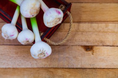 Tahta arka planda bir kutuda sarımsak. Sebze topla..