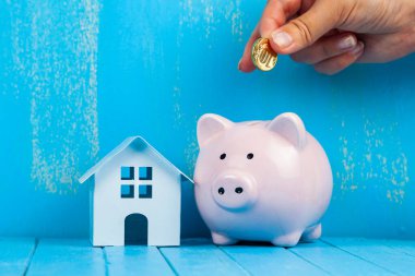 Kadın eli domuz kumbarasına bozuk para koyar. Gayrimenkul için tasarruf.