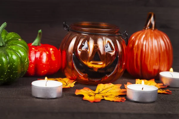 Halloween. Pumpkins glow in the dark. Still life with pumpkins, candles and autumn leaves on a wooden background