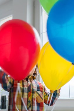 Boy with balloons in front of window 