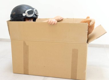 Mutlu çocuk bir kutu içinde uçan ve onun oyuncak ile bir şapka giyiyor 