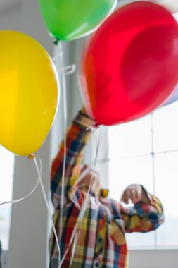 Boy with balloons in front of window 