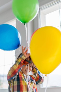 Boy with balloons in front of window 