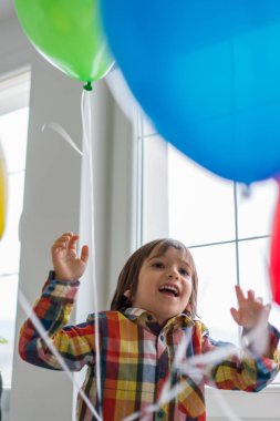Boy with balloons in front of window 