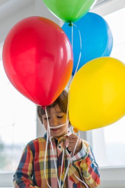 Boy with balloons in front of window 