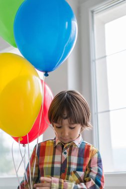 Boy with balloons in front of window 