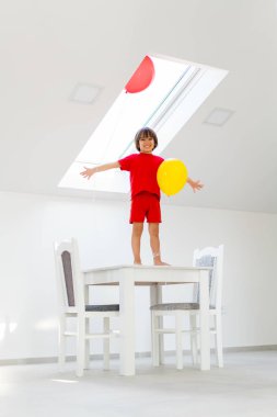 Bir balon tutarken çocuk bir masada ayakta