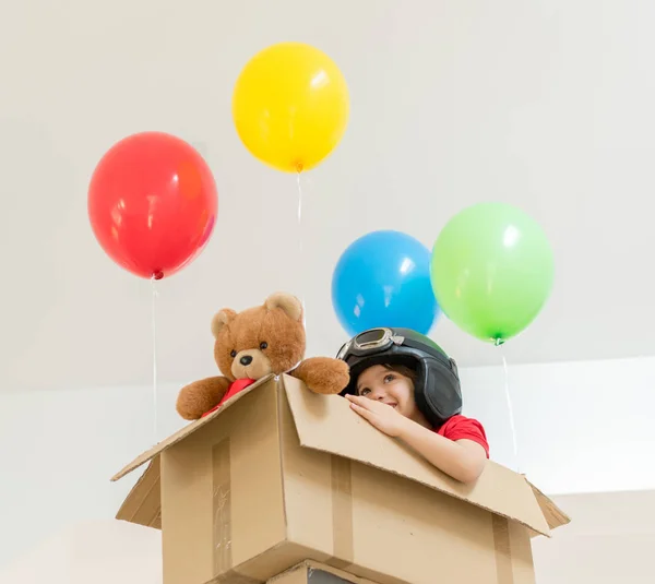 Niño feliz sentado en su caja imaginándose volando — Foto de Stock