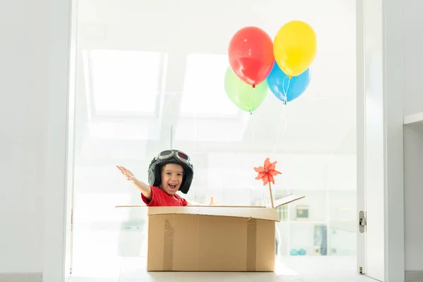 Menino feliz sentado em sua caixa imaginando-se voando — Fotografia de Stock