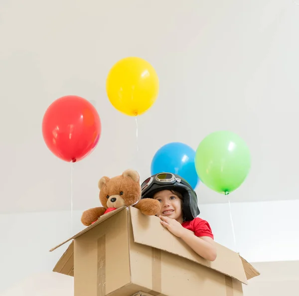 Niño feliz sentado en su caja imaginándose volando — Foto de Stock