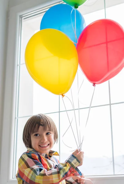 Ragazzo con palloncini davanti alla finestra — Foto Stock