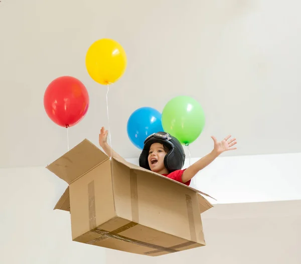 Happy boy sitting in his box imagining him self flying — Stock Photo, Image