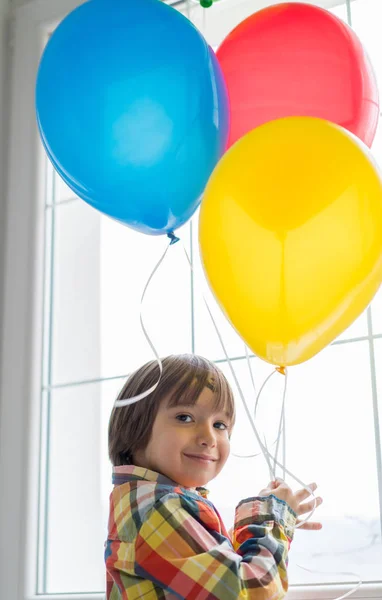 Menino com balões na frente da janela — Fotografia de Stock