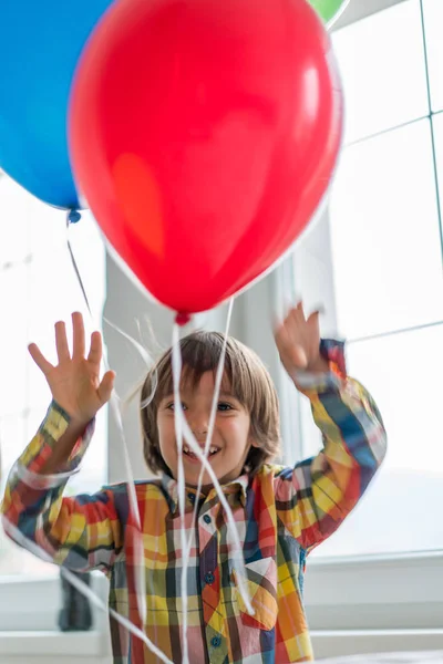 Хлопчик з повітряними кулями перед вікном — стокове фото