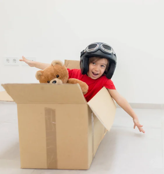 Счастливый мальчик летит в коробке и носит шляпу со своей игрушкой — стоковое фото