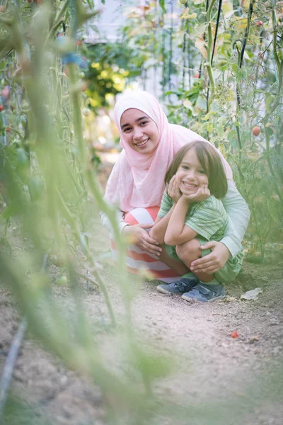Fiatal Arab muszlim lány kis gyermek dolgozik greenhous — Stock Fotó