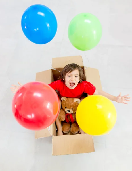 Κορυφαία θέα του αγοριού που κάθεται σε κουτί με μπαλόνια — Φωτογραφία Αρχείου