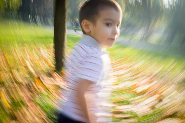 Motion imagem turva de menino correndo no parque de outono — Fotografia de Stock