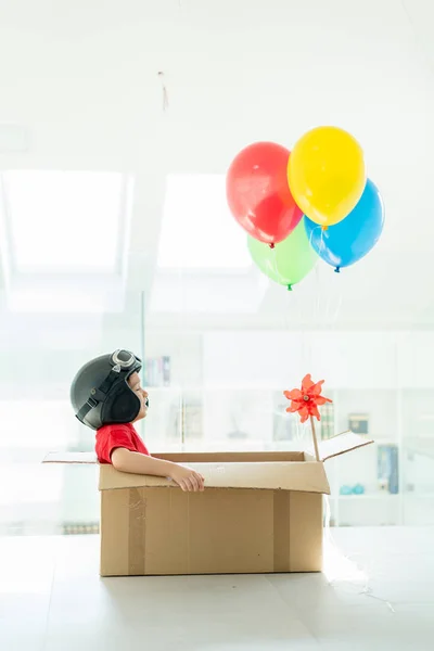 Menino feliz sentado em sua caixa imaginando-se voando — Fotografia de Stock