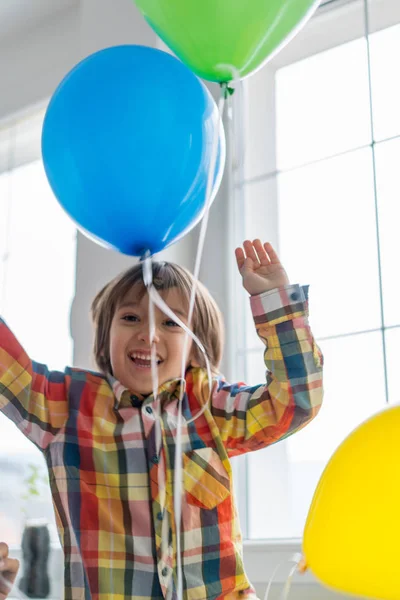 Boy with balloons in front of window — Stok fotoğraf