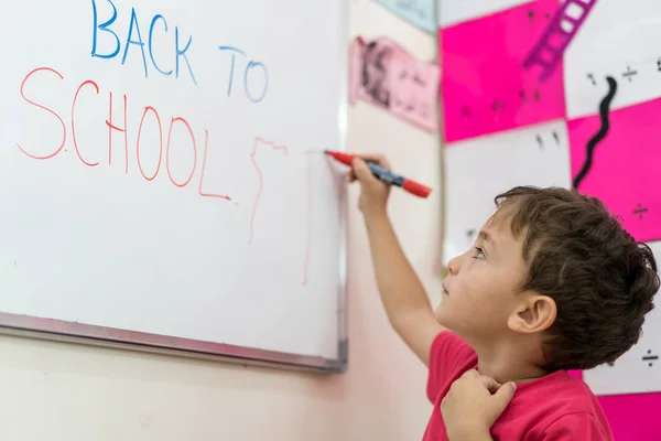 Junge schreibt auf Whiteboard zurück in die Schule — Stockfoto