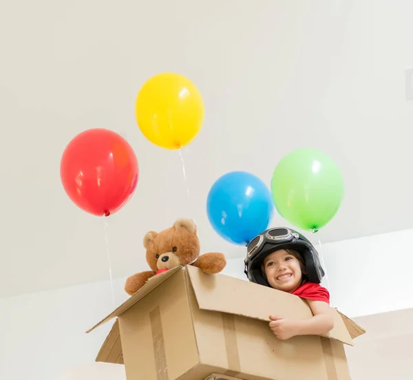 Menino feliz sentado em sua caixa imaginando-se voando — Fotografia de Stock