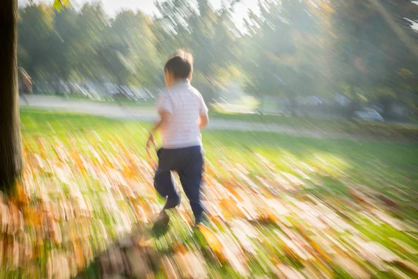 Motion imagem turva de menino correndo no parque de outono — Fotografia de Stock