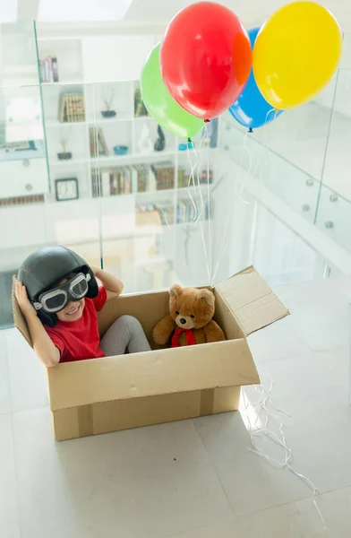 Niño con su oso volando en una caja con globos Fotos De Stock