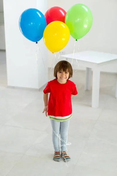 Pojke stående och hålla ett gäng ballonger i handen Stockfoto