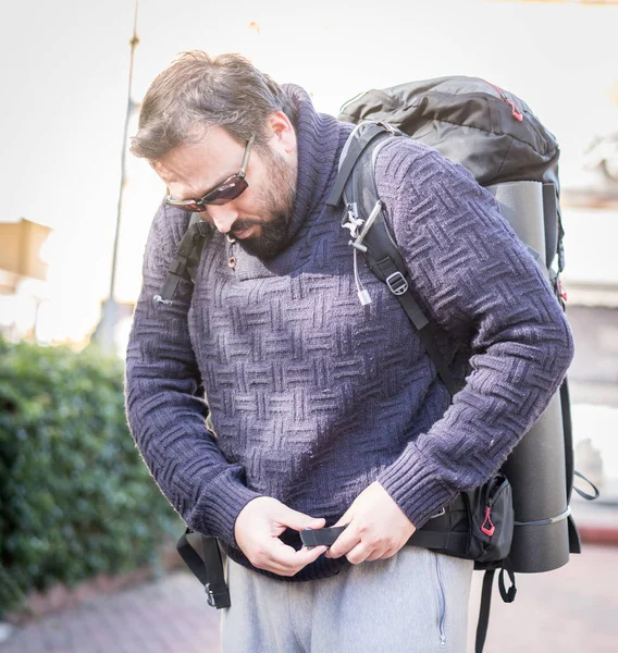 Мужской турист чинит рюкзак на улице — стоковое фото