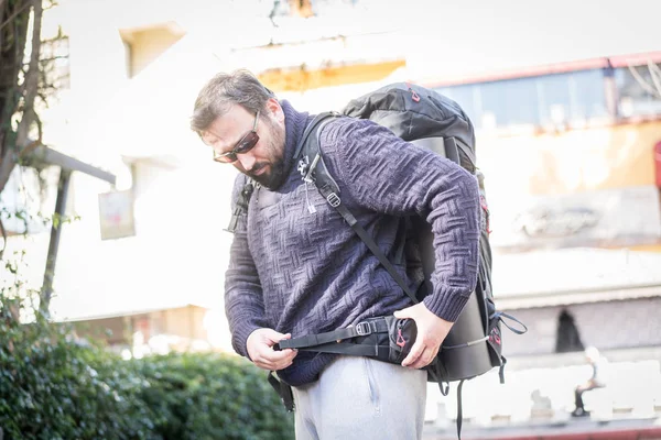 Мужской турист чинит рюкзак на улице — стоковое фото