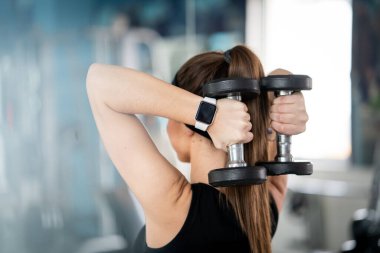 Siyahlı kadın GZM 'de dambıl kullanıyor.