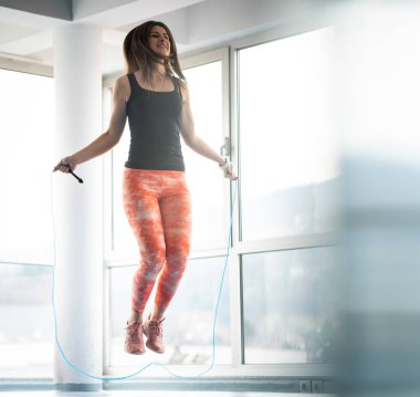 Spor salonunda ip atlayan güzel bir kadın.