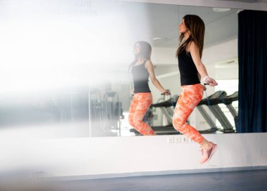 Spor salonunda ip atlayan güzel bir kadın.