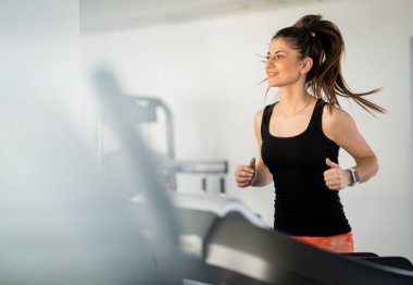 Spor salonunda koşu bandı kullanan atletik güzel kadın.