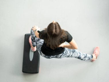 Formda kadın spor salonunda ekipman kullanarak esniyor.