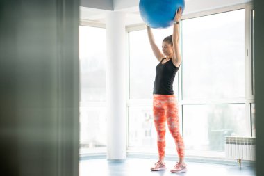 Spor salonunda tıp topu kullanan güzel bir kadın.